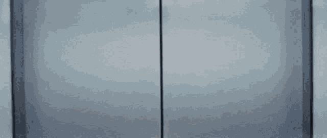 a woman wearing glasses is peeking out of a door