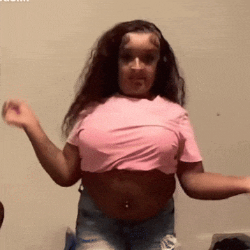 a woman wearing a pink crop top and blue shorts is dancing