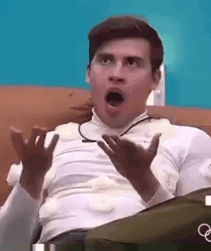 a man is sitting on a couch with his mouth open and his hands up .