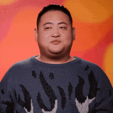 a man wearing a blue sweater with flames on it looks serious