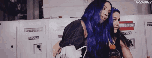 two women with blue hair standing next to each other with a bottle of orange juice