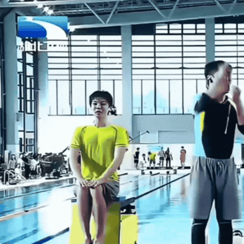 a man in a yellow shirt is sitting on a yellow block in front of a swimming pool