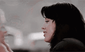 a woman with long black hair is talking to another woman in a restaurant .
