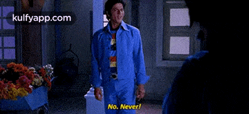 a man in a blue suit is standing next to a pillar and says no never !