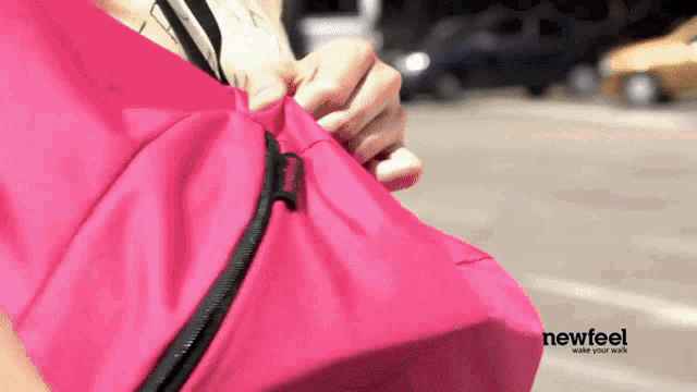 a woman is holding a pink bag that says newfeel
