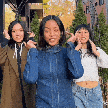 three women are posing for a picture with their hands on their ears
