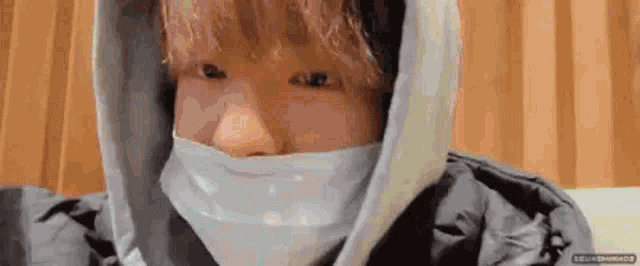 a close up of a person wearing a hoodie and a mask covering their face .