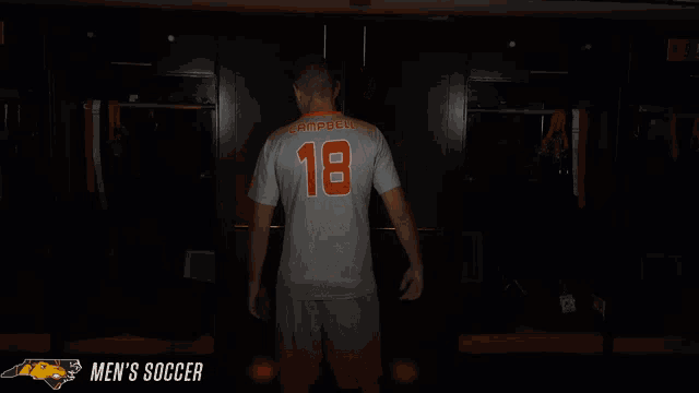 a man in a campbell 18 jersey stands in a dark room