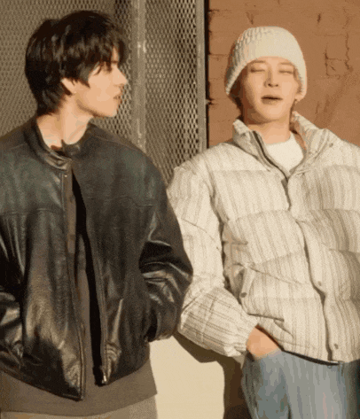 two men standing next to each other one wearing a leather jacket