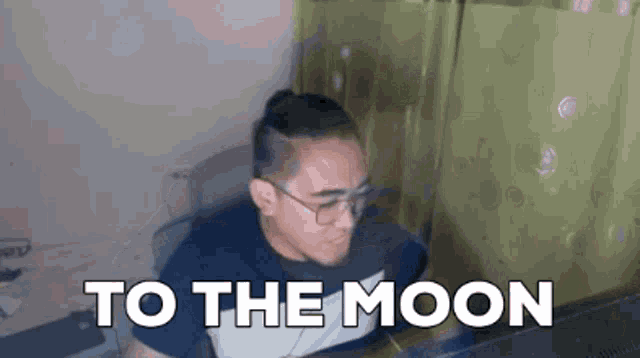 a man with glasses sits in front of a computer screen with the words to the moon written on it