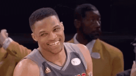 a basketball player is smiling and looking at the camera while standing next to a man in a suit .