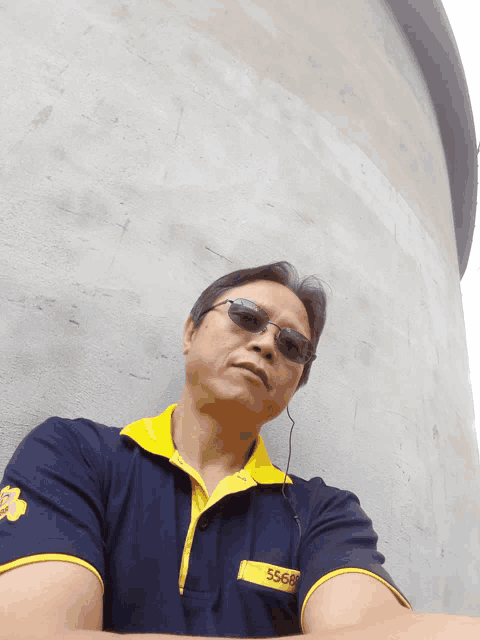a man wearing sunglasses and a blue shirt that says 56688