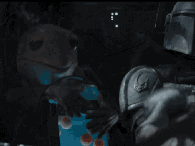 the mandalorian is holding a baby yoda in his arms