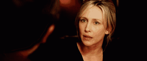a woman is talking to a man in a dark room and looking at him .