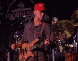 a man playing a bass guitar in front of a sign that says north sec