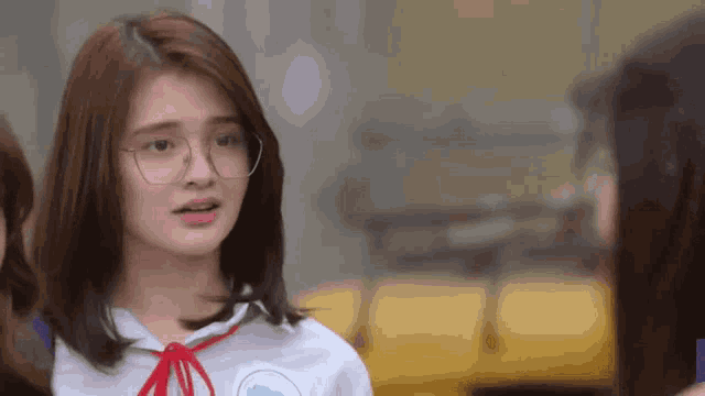 a girl wearing glasses and a white shirt with a red bow on it