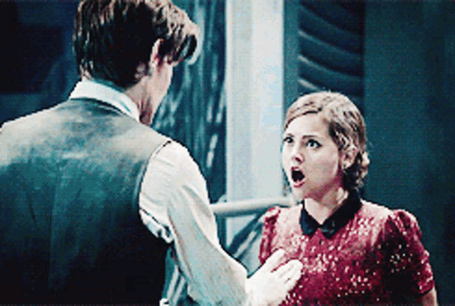 a man and woman are standing next to each other and the woman is wearing a red dress