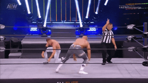 two men are in a wrestling ring with a referee and a sign that says aew dynamite