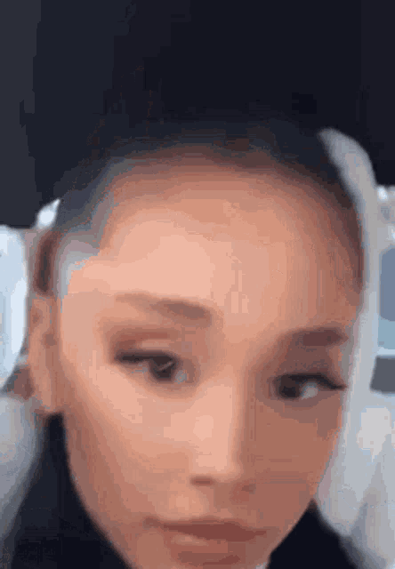 a close up of ariana grande 's face with her eyes closed and her hair in a bun .