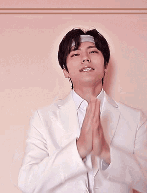 a young man wearing a headband and a white jacket is making a funny face