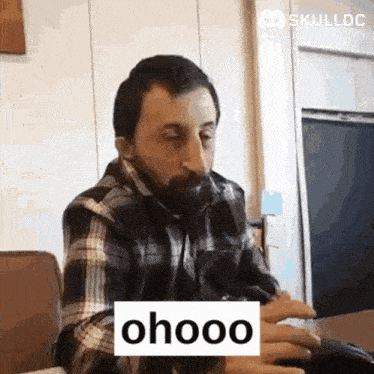 a man in a plaid shirt is sitting at a table with a sign that says ohooo on it .