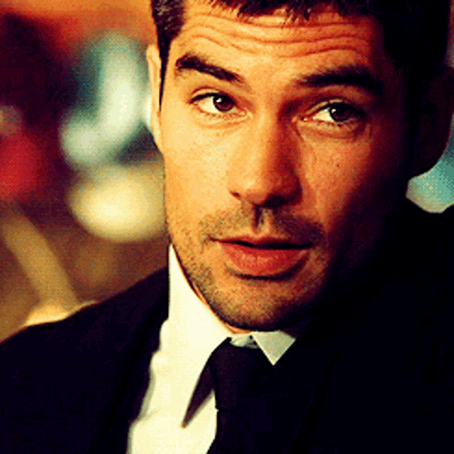 a close up of a man 's face with a suit and tie