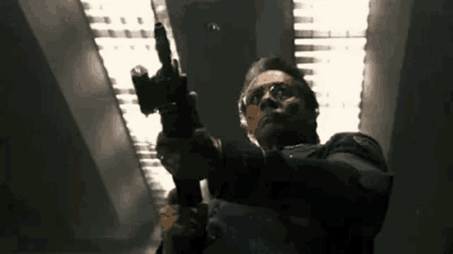 a man in a police uniform is holding a gun in a dark room .