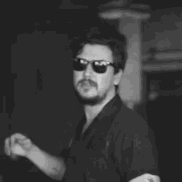 a black and white photo of a man wearing sunglasses and a name tag that says j.