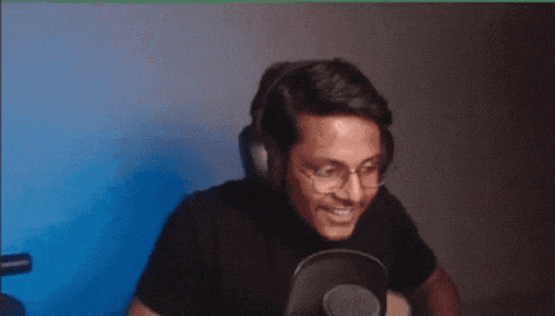 a man wearing headphones and glasses is eating a piece of food in front of a microphone .