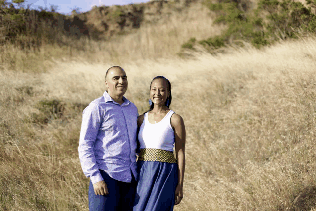 a man and woman are standing in a field of tall grass