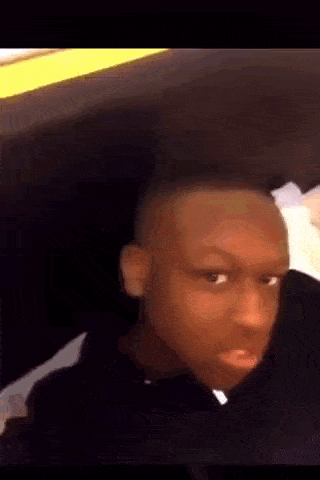 a young boy with a shaved head is making a funny face .