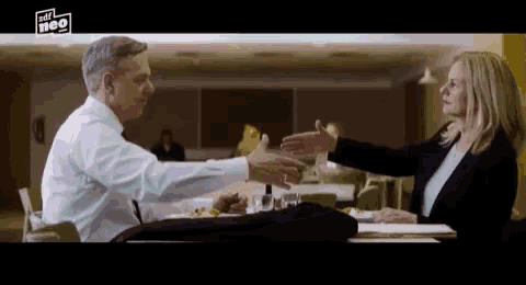 a man and a woman are sitting at a table talking to each other .
