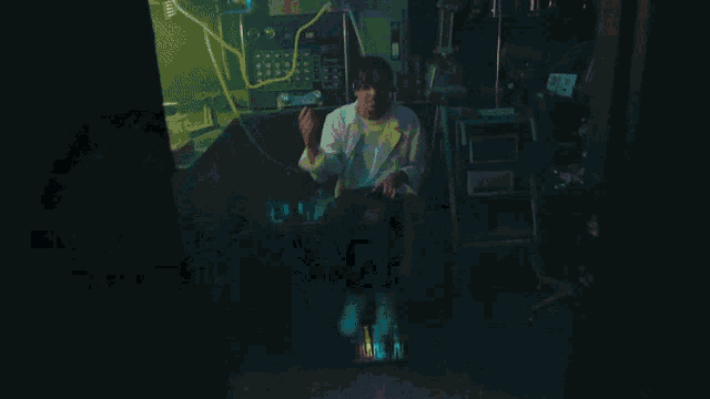 a man in a lab coat sits in a dark room with a lightning bolt behind him