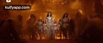 a woman in a silver dress is dancing in front of a group of people .