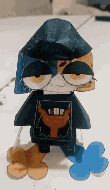 a paper toy of a cat wearing glasses and a black shirt with a picture of a bull on it