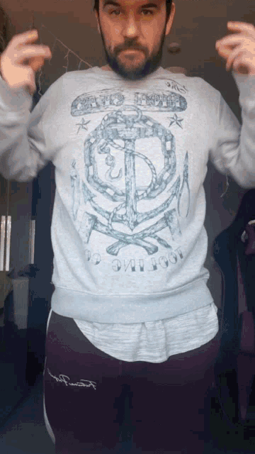 a man with a beard wears a sweatshirt with an anchor on it that says ' no one loves you '