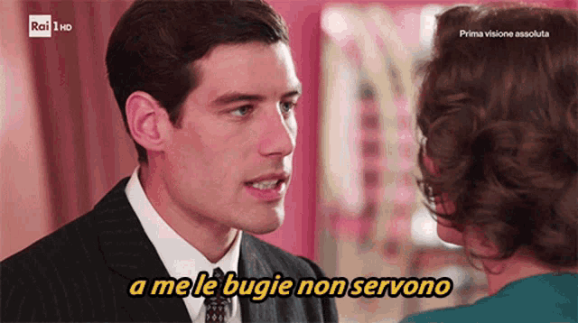 a man in a suit and tie talks to a woman with the words a me le bugie non servono above him