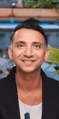 a man wearing a black jacket and a white shirt smiles