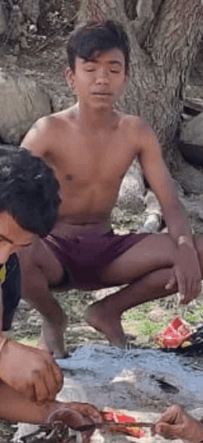 a group of young men are kneeling down under a tree .