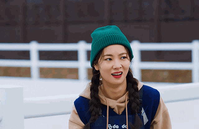 a woman wearing a green beanie and a blue apron that says " do do "