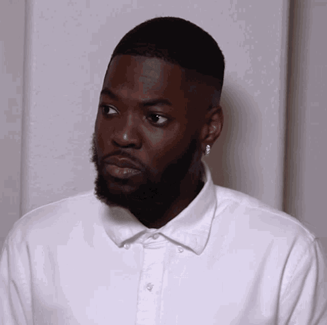 a man with a beard wearing a white shirt and earrings