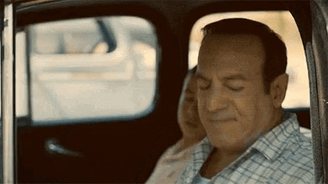 a man and woman are sitting in the back seat of a car .