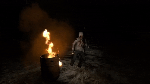a man is laying on the ground in front of a fire