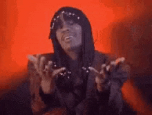 a woman wearing a hat and sunglasses is making a funny face with her hands in the air .