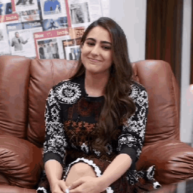a woman is sitting in a leather chair smiling .