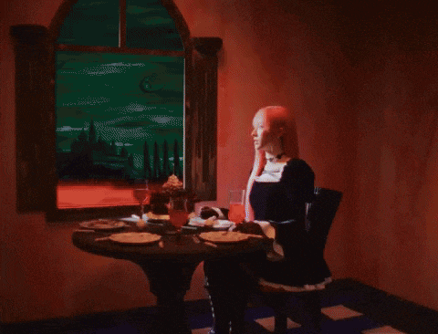 a woman with pink hair is holding a lit match in her hand in a dark room .