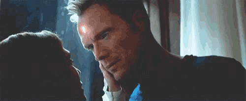 a man and a woman are looking into each other 's eyes and the man has a light on his forehead