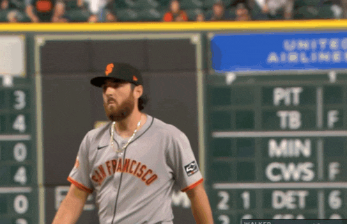 a san francisco baseball player stands in front of the scoreboard