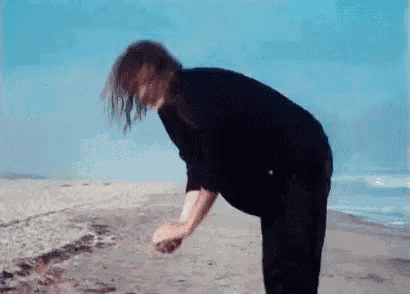 a man in a black shirt is standing on the beach