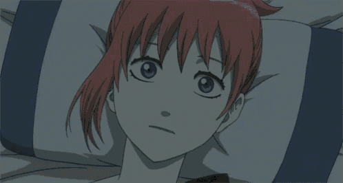 a girl with red hair and black eyes is laying on a pillow